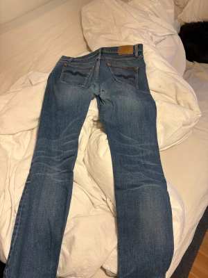 Blå jeans från Nudie Jeans, straight fit - Säljer nu ett par nudie jeans som bara blivit liggandes då nya har köpts! Inte skinny eller slim men inte heller helt raka så något mittemellan  Storlek w31 L34