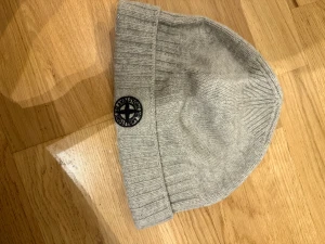Stickad mössa Stone Island - Stickad grå mössa från Stone island. Använd men i bra skick. Kan skicka fler bilder!
