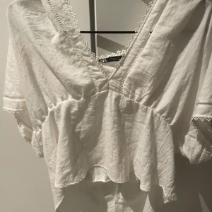 Vit blus från Zara - Säljer en vit omlottblus från Zara med v-ringning och volangdetaljer. Nyskick!!