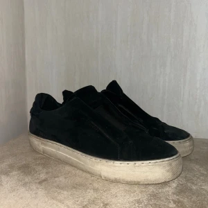 Svarta sneakers från Axel Arigato - Svarta sneakers från Axel Arigato i mocka med minimalistisk design och rund tå. Skorna har används i några månader och finns lite delar som e trasiga 