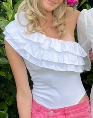 Vit one shoulder body med volanger - Säljer en vit one shoulder body med volanger över axeln. Är storlek M men passar mer som en xs/s men är är stretchigt matrial. Knappt använd och bra sick. Priset kan diskuteras vid snabb affär 