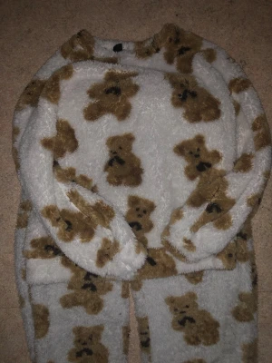 Fluffigt set med mjukisbyxa och tröja - Supergosiga mjukisbyxor och tröja från Dazy i storlek S. Byxorna är vita med bruna nallar över hela och har en riktigt fluffig och mjuk känsla. Perfekta för att chilla hemma och hålla sig varm under kyliga dagar.