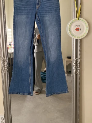Blå bootcut jeans  - Säljer ett par klassiska blå jeans från 157 med bootcut passform och låg midja. Jeansen har fem fickor, snygga kontrastsömmar och är tillverkade i slitstarkt denimtyg. Perfekta för dig som gillar retrovibbar och vill ha ett par riktigt schyssta jeans. Length short 