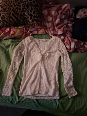 Vit spetsblus med v-ringning - Säljer en superfin vit spetsblus från Gina Tricot. Blusen har långärmade spetsärmar, v-ringad hals och är figurnära i modellen. Perfekt för dig som gillar romantiska detaljer och vill ha något extra till outfiten.