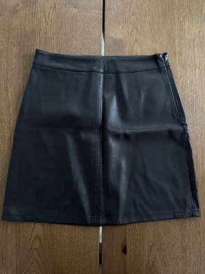 Svart kort kjol i skinnimitation - Svart kort kjol från Gina Tricot i skinnimitation. Storlek 36. Knappt använd så i jättefint skick.