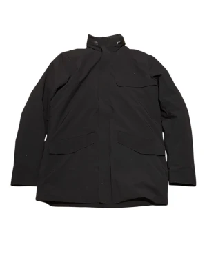 J.Lindeberg Men's Winter Jacket / Parka - Black - Size M - Selling a premium black jacket from the Swedish brand J.Lindeberg. This is a high-quality piece that combines a sleek, minimalist look with technical functionality. Perfect for autumn and winter.  Brand: J.Lindeberg  Color: Classic Black  Features: Hood with logo detail, zip and button closure, and the iconic JL bridge logo on the sleeve.  Interior: Fully lined with a quilted J.Lindeberg monogram pattern.  Condition: Excellent condition.