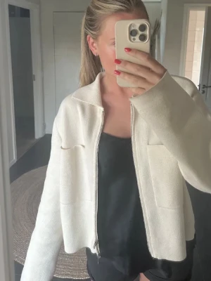 Krämvit cardigan från Åhléns  - Krämvit Cardigan med dragkedja, modell CROSS. Från Åhléns.  Helt ny, aldrig använd.  Endast legat i garderoben.  Storlek S men passar både S och M. Köpt för 599kr 