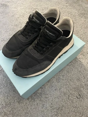 Philippe Model  - Philippe Model sneakers i klassisk modell med snygga detaljer i mocka och textil. Skorna har svart snörning, vit innersida och en vit sula som ger en clean kontrast. Perfekta för dig som gillar stilrena och tidlösa sneakers. Använda fåtal gånger. Hör av er vid frågor.