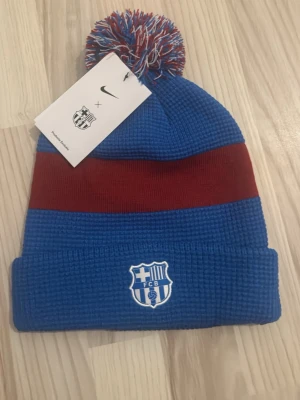  Helt ny barcelona mössa - En helt ny fc barcelona mössa med tagg på, mössan är blå och röd med ränder på.