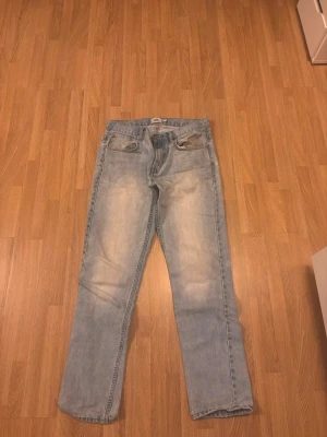 Ljusblå jeans från 157, W32 L32 - Ljusblå jeans från 157 med klassisk femficksdesign och raka ben. Säljer ett par jeans i fint skick. Det finns en lagning mellan benen där byxorna tidigare gick sönder, men den är profesionellt/ordentligt sydd och håller bra. Inget som påverkar användningen.