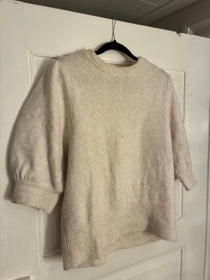 Beige stickad tröja från H&M - Mysig beige stickad tröja från H&M i storlek L. Tröjan har trekvartsärmar med puff och bred ribbad mudd vid ärmslut och nederkant. Perfekt för lager på lager under höst och vinter. Enkel, stilren och superenkel att matcha.