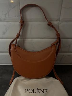 Polène brun axelväska i skinn - Säljer en snygg brun axelväska från Polène i  skinn.  Dustbag från Polène medföljer och rem. Fått i julklapp därav priset.