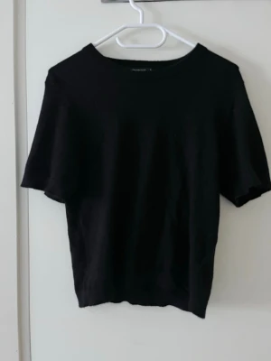 Svart finstickad topp Gina Tricot - En svart finstickad topp från Gina Tricot i storlek S. Modellen har rund halsringning och korta ärmar. Enkel och clean design som funkar till allt, i mjukt stickat material.