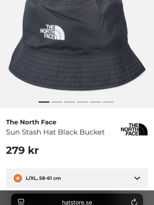 Svart bucket hat från The North Face - Säljer en svart bucket hat från The North Face med klassisk vit logga framtill. Hatten är tillverkad i lätt syntetmaterial och har en enkel, stilren design. Perfekt för soliga dagar och streetwear-stil. Storlek L/XL (58-61 cm).