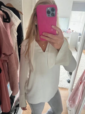 Blus långärmad - Säljer en stilren vit blus med långa ärmar och snygga knytband i halsen. Blusen har en lös passform och är tillverkad i ett mjukt, lätt material som ger ett elegant fall. Pris kan diskuteras💕