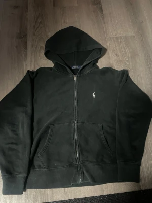 Ralph lauren hoodie - Säljer en snygg svart Ralph lauren hoodie! Perfekt för kallare dagar och passar till allt. Säljer den då den är för liten för mig. Den är lite urtvättad men inte mycket. Den har lite smutsfläckar men den går enkelt att ta bort. Annars är de inga större problem med hoodien. Den står i storlek M men har krympt till storlek S. Den är självklart äkta! Mitt utgångspris: 599:) Hör av dig vid fundering:) Frakt samma dag som köp! Snabb affär = bättre pris:)