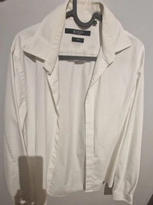 Vit skjorta från Tiger of Sweden slim fit - Klassisk vit skjorta från Tiger of Sweden i storlek 40. Skjortan är tillverkad i bomull och har en stilren design med knappar framtill och lång ärm. Perfekt för dig som gillar en clean och tidlös look.