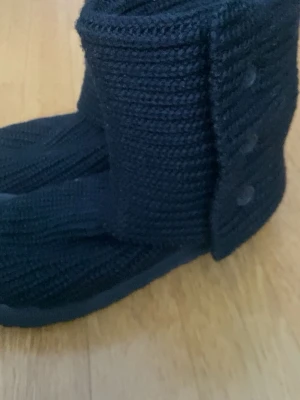 Svarta stickade UGG skor - Jättefina stickade UGGS perfekt nu till vintern! Färgen passar med allt. De går att använda på två olika sätt, med eller utan knäppt. De är i mycket bra skick och har inga tydliga tecken på användning💗