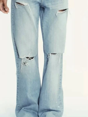 Ljusa ripped wide jeans - Säljer ett par ljusblå jeans med breda ben och slitna detaljer på låren och knäna. Modellen har en loose passform och är tillverkad i klassiskt jeanstyg. Perfekt för dig som gillar en avslappnad och trendig stil. Från Zara storlek 34, väldigt fint skick 