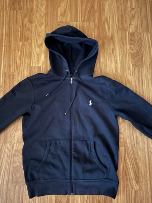 ralph lauren zip hoddie - Säljer en Ralph lauren zip hoddie som är i ett fint skick och minimalt använd. Tröjan är köpt från zalando för 2200 kr för några månader sen. Tröjan passar dig mellan 173-178 cm, är själv 179 och den passar bra.  Hör av er vid frågor😊