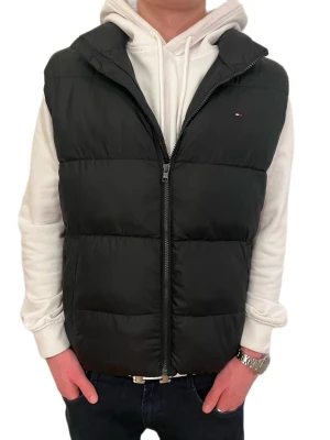 Tommy Hilfiger Essential Padded Vest i svart polyester - Säljer en svart dunväst från Tommy Hilfiger med hög krage och diskret logga på bröstet. Västen har två sidofickor och dragkedja framtill. Materialet är syntet och polyester, perfekt för kyliga dagar. Sprillans ny och ej använd!