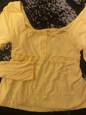 Gul långärmad topp med knappar  - Gul långärmad topp med knappar framtill. Passar S och XS