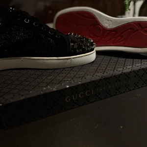 Svarta sneakers med nitar från Christian Louboutin - Säljer ett par sällsynta Christian Louboutin sneakers i utmärkt skick. Dessa är extremt svåra att få tag på och gör ett starkt intryck med sina ikoniska röda sulor och lyxiga design. Storlek: EU 42. Kommer med extra skosnören samt en box som, ej tillhör dom här skorna. Nypris är över 25000 tusen – passa på att fynda till ett betydligt bättre pris.  Perfekta för dig som uppskattar exklusivt mode och sneakers som verkligen sticker ut.  Skicka DM för mer info eller vid intresse.