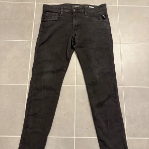Replay svarta slim jeans - Snygga svarta jeans från Replay med klassisk femficksdesign och smal passform. Jeansen har diskreta sömmar och en stilren look som passar till det mesta. Tillverkade sopm vanligt i slitstarkt jeanstyg med Replay-logga på fickan.