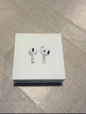 Apple AirPods 4 trådlösa hörlurar - Säljer ett par vita Apple AirPods 4 i originalförpackning. De är trådlösa in-ear hörlurar med stilren och kompakt design. Perfekta för musik, samtal och vardagsbruk. Laddningsetui och USB-C kompatibilitet ingår.