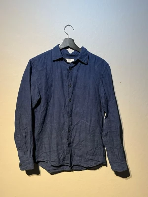   Uniqlo linneskjorta  - Snygg mörkblå LINNE SKJORTA  från Uniqlo i luftigt linne. Klassisk krage, knäppning framtill och långa ärmar. Perfekt för dig som gillar en enkel och stilren look. Passar till både jeans och chinos.