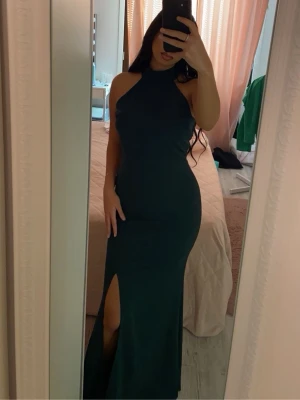 Mörkgrön långklänning med slits - Säljer en elegant mörkgrön långklänning från Zalando – WAL G, storlek 38. Klänningen har hög hals, ärmlös design och en snygg slits framtill. Den är använd en gång och i mycket bra skick. Perfekt för dig som vill sticka ut på festen! Originalpris: 519 kr🌸