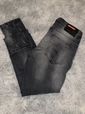 Grå slitna jeans från Dsquared2 - Säljer ett par grå jeans från Dsquared2 med slitningar och tvättade detaljer. Jeansen har klassisk femficksmodell, normal passform och är tillverkade i bomull med en snygg skinny siluett. Perfekta för dig som gillar en edgy streetstil.