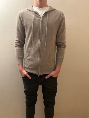 Beige cashmere hoodie från John Henric  - Säljer denna beiga cashmere hoodien från John Henric i 100% cashmere. Aldrig tvättad och vårdsamt använd, köpt på NK i Göteborg. Kom gärna med bud!