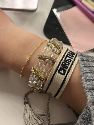 Glittrig armband med pärlor och guld - Säljer ett glittrigt armband med stora, transparenta pärlor och guldfärgade detaljer. Armbandet har flera rader av gnistrande stenar och guldfärgade, en sten har dock fallit av💕