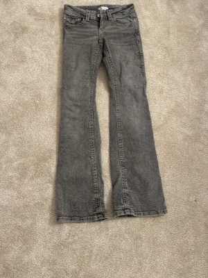 Grå bootcut jeans från Gina Tricot - Säljer ett par gråa bootcut jeans från Gina Tricot i storlek 146. Jeansen har klassisk femficksdesign, normal passform och är tillverkade i mjukt denimtyg. Perfekta för dig som gillar en avslappnad men ändå snygg look.