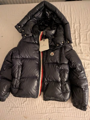 Moncler puffer - Här har vi en riktigt nice Moncler puffer jacka! Den är lagad när den varit trasig på ett ställe nära cartonen, men ingen fara inget man ser utanför jackan och den är EXTREMT varm och kommer i sin fina Moncler påse o lappar! Storlek 158/165)
