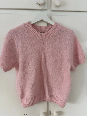 Ljusrosa stickad tröja Gina Tricot - Supersöt ljusrosa stickad tröja från Gina Tricot med korta ärmar och ribbade muddar. Mjuk och fluffig. Storlek M🩷