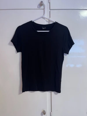 Soft touch T-shirt  - En enkel soft touch svart T-shirt  med rund halsringning och korta ärmar. Modellen är rak och har en clean look som passar till allt. Perfekt basplagg för garderoben.