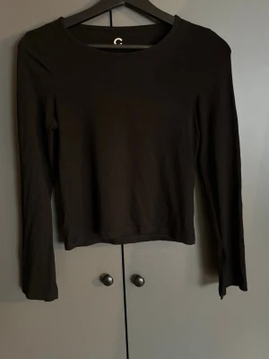 Svart långärmad topp från C - En enkel och stilren svart långärmad topp från Cubus. Modellen har rund halsringning och är rak i passformen. Perfekt att matcha med jeans eller kjol för en clean look.