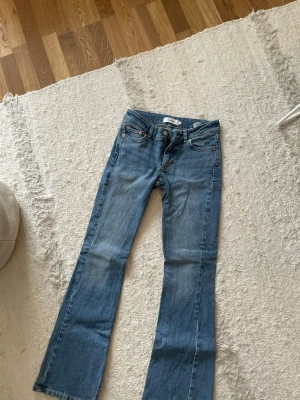 Blå bootcut jeans från Junkyard - Snygga blå bootcut jeans med klassisk femficksdesign och ljus tvätt. Jeansen har normal passform och är tillverkade i mjukt denimtyg av bomull. Perfekta för dig som gillar en retroinspirerad look med utsvängda ben.