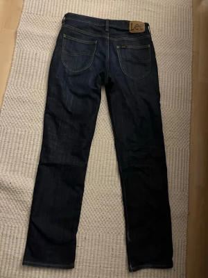 Mörkblå lee jeans med snygg wash endast använda ett fåtal gånger - Säljer dessa jättensygga lee jeans som jag endast användt några gånger därför är de i superskick, modellen heter lee west och de är i storlek 30:32. Riktigt bra pris då de som sagt är i jättebra skick och jättesnygga!