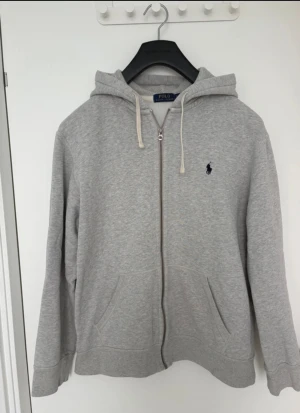 Grå hoodie från Polo Ralph Lauren XL - Grå hoodie från Polo Ralph Lauren i storlek XL men passar L. Nyskick! Använd endast ett fåtal gånger! 