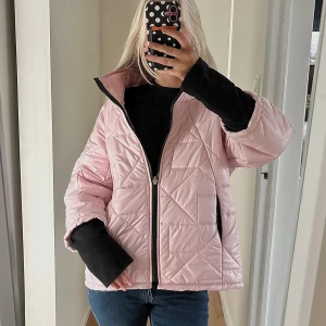Ljusrosa quiltad pufferjacka - Säljer en ljusrosa pufferjacka med quiltad design och svart dragkedja framtill. Jackan har en loose passform, hög krage och två sidofickor med svarta detaljer. Perfekt för dig som vill ha en chill och snygg look under kyliga dagar. Vet inte märke