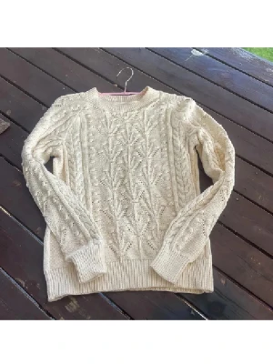 Beige stickad tröja Part Two S - Säljer en beige stickad tröja från Part Two i storlek S. Tröjan har ett snyggt kabelstickat mönster med detaljer på både fram- och baksida samt ribbade muddar vid hals, ärmslut och nederkant. Perfekt för dig som gillar mysiga och stilrena plagg.