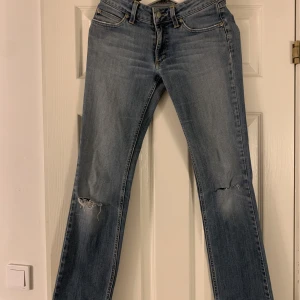 Lågmidjade jeans - Ett par Lågmidjade vintage jeans som har två hål på knäna.