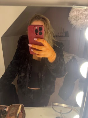 Svart pälsjacka från Vero Moda - Mysig svart pälsjacka från Vero Moda med huva och tryckknappar framtill. Jackan är fluffig och har en snygg, lite kortare passform med huva. Perfekt för kyliga dagar när du vill vara både varm och stylish🤗