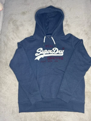 Riktigt snygg superdry hoodie-eftertraktad  - Sjukt snygg vintege superdry hoodie med fet text på bröstet. Storlek S. Skickas inom 24H efter köp🙌🏼 SKICKAR MED POSTNORD ELLER INSTABOX‼️ hör av er vid frågor osv🤩