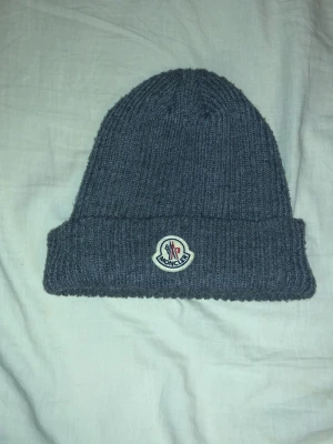 Grå Moncler mössa - Snygg och stilren Moncler-mössa i klassisk grå färg. Mjuk och skön, passar perfekt till vardags och håller värmen bra. I mycket fint skick, sparsamt använd. Äkta Moncler. Passar det mesta tack vare stretchig modell. Skickas snabbt 💫
