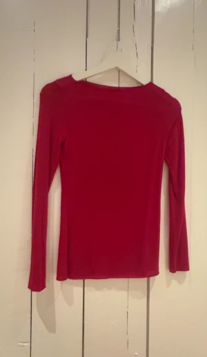Röd långärmad topp från Intimissimi - Säljer en röd långärmad topp från Intimissimi i ultralätt material med kashmir. Toppen har en enkel, slim passform och rund halsringning. Perfekt för dig som gillar mjuka och sköna plagg med stilren look. Aldrig använd bara att jag tagit av lappen, perfekt nu till jul, köpte den för 500kr