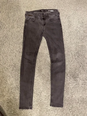 Replay svarta skinny jeans  - Säljer ett par svarta skinny jeans från Replay med snygg dragkedjedetalj vid fickan fram. Jeansen har klassisk femficksdesign, smal passform och är tillverkade i stretchigt jeanstyg för en bekväm känsla. Perfekta för dig som gillar en tight och modern look.